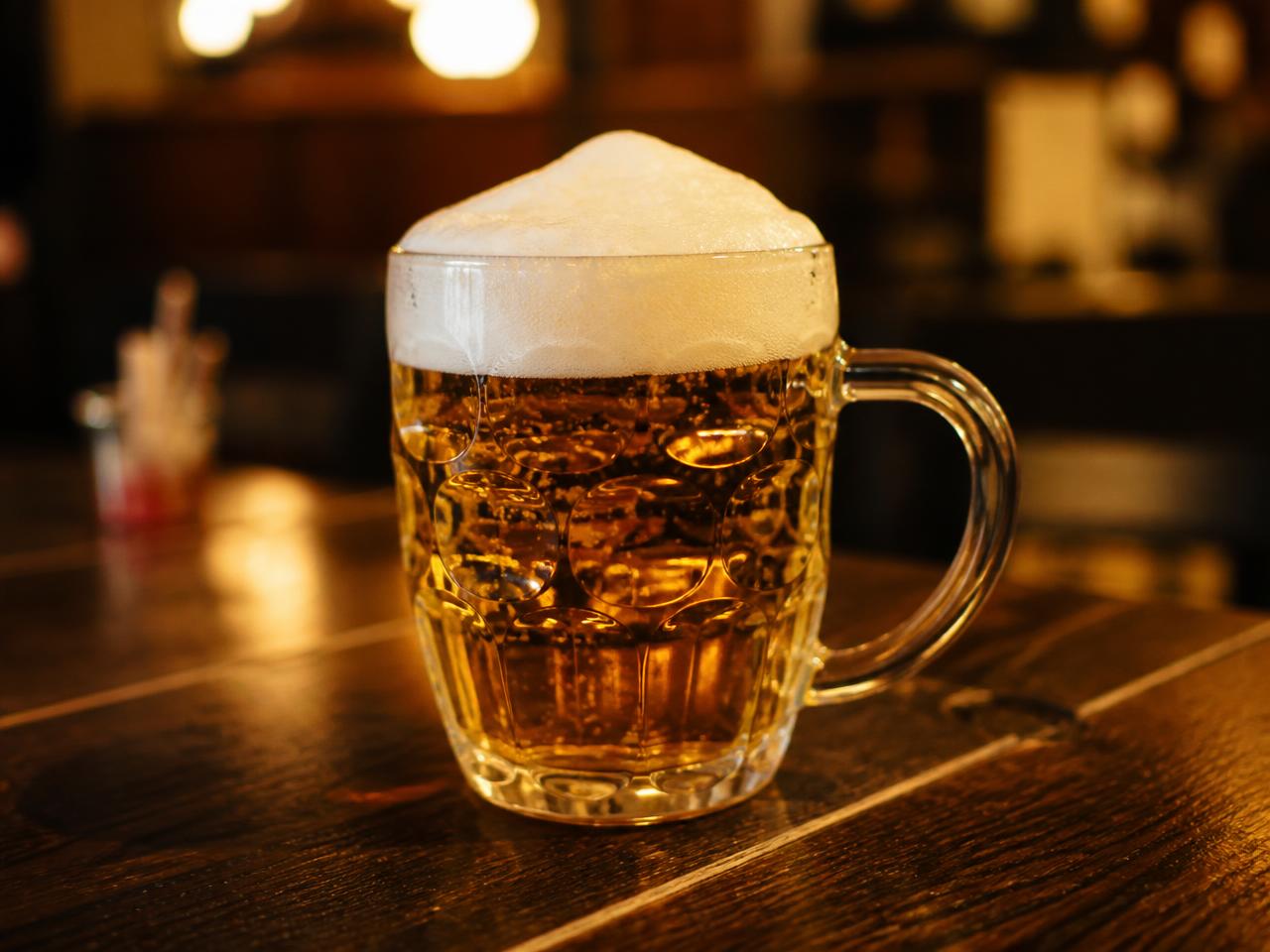 Točené pivo s pěnou na dřevěném stole v hospodě